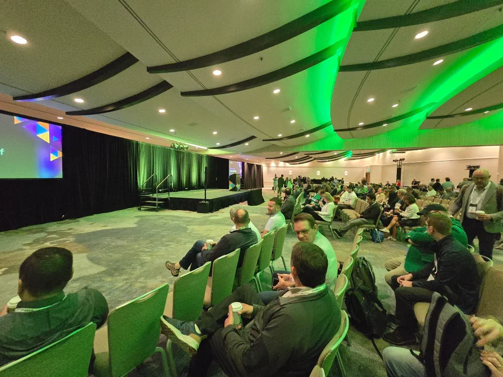 A screen displays “veeamon Welcome to Partner Kickoff” with colorful abstract shapes in the background.